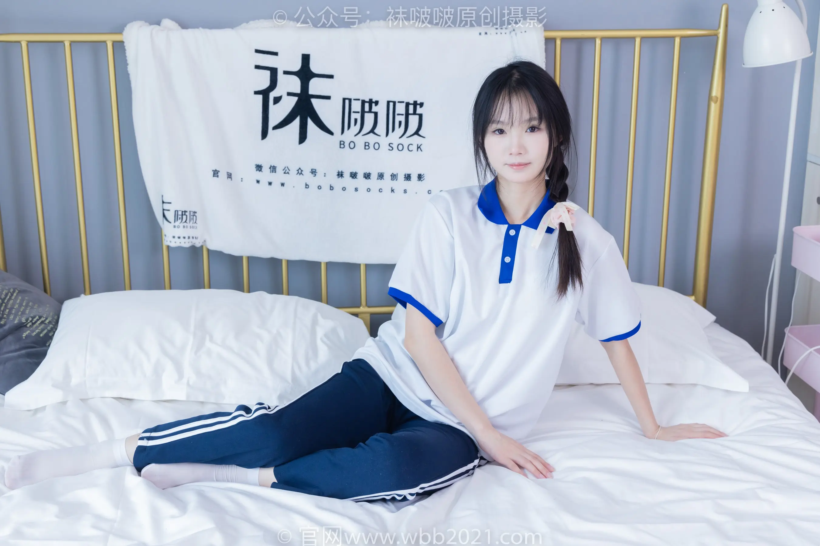 阿拉夫德亚洲妇女坐在床上，穿着白色和蓝色的衬衫