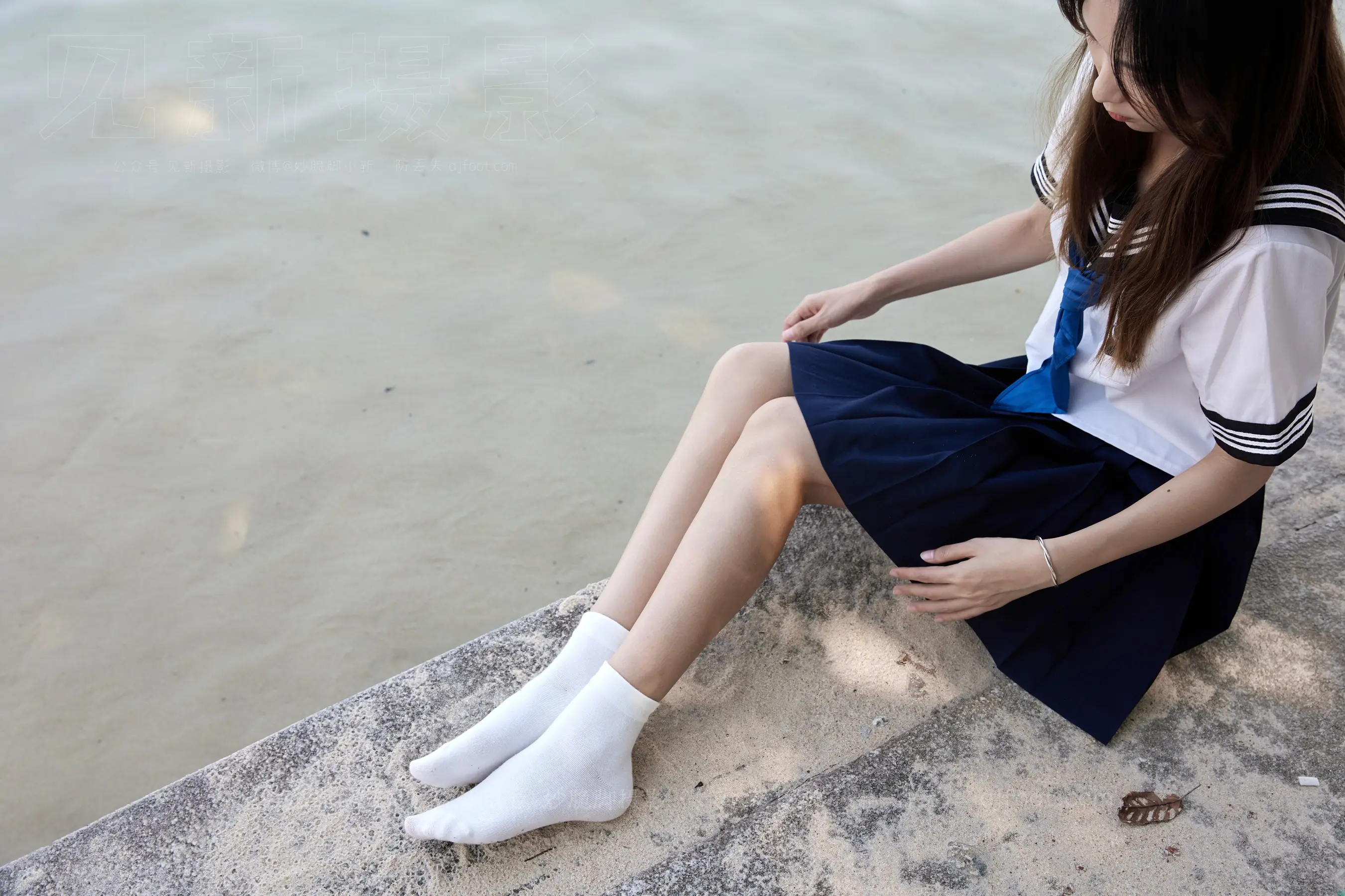 有一个女人坐在水边的壁架上