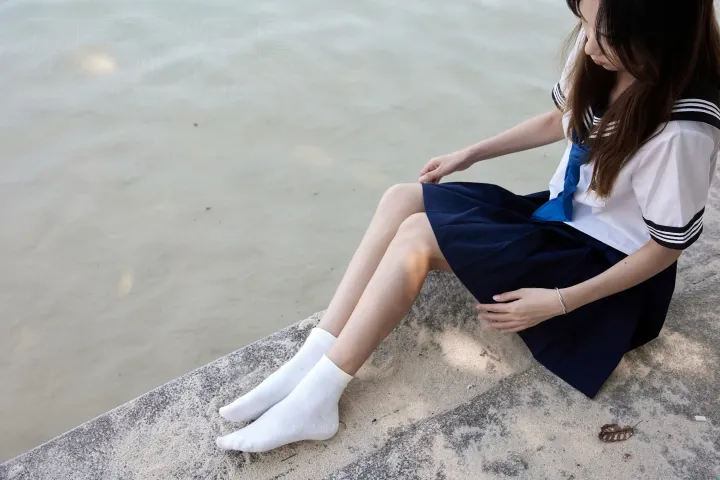 有一个女人坐在水边的壁架上