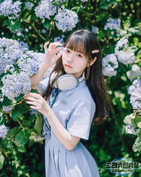 一个穿着蓝色连衣裙的女人站在一丛紫色的花丛前