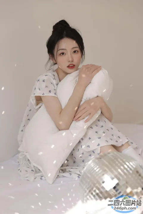 有个女人坐在床上，手里拿着一个枕头