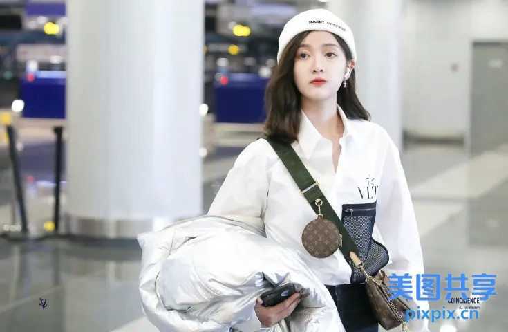身穿白衬衫的阿拉夫女子拎着包和手机