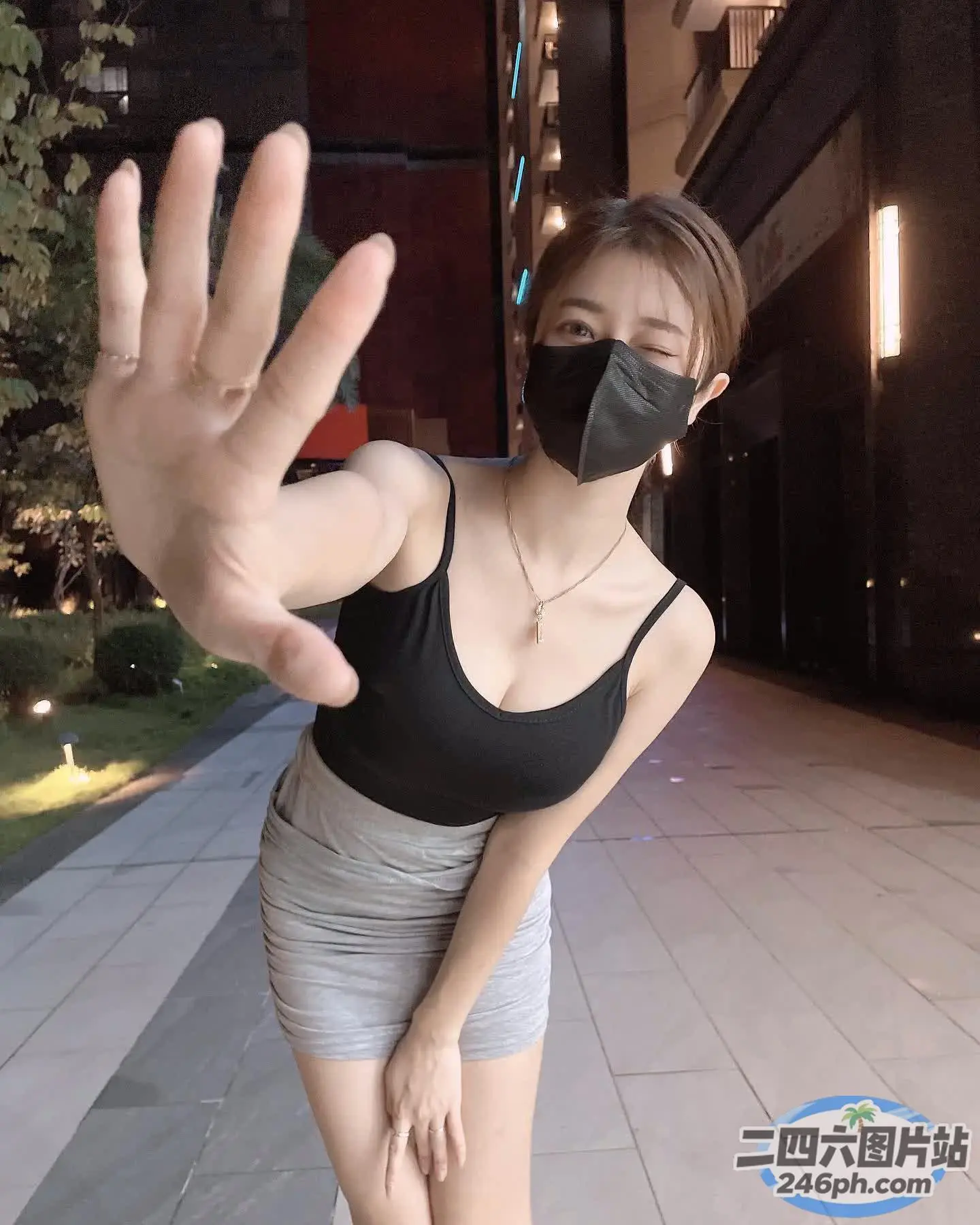 戴着黑色口罩、身穿黑色上衣的女人站在人行道上