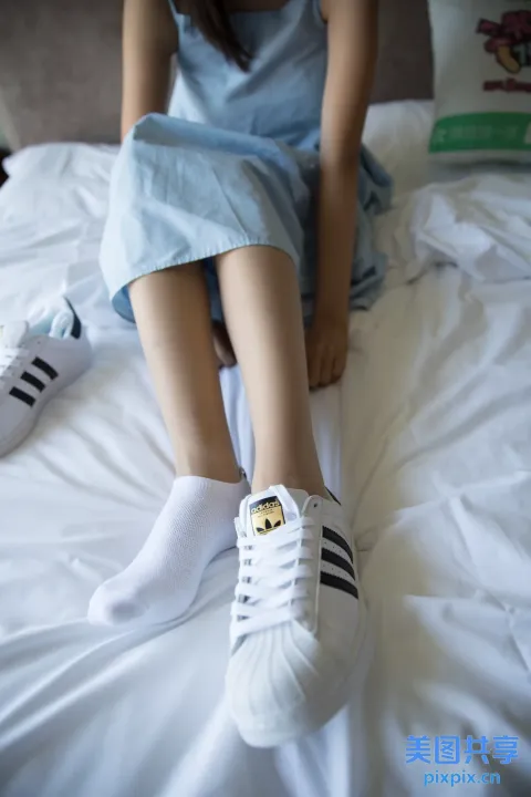 坐在床上的阿拉夫妇，穿着白鞋，拿着一本书