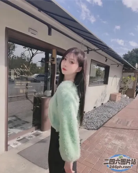 身穿绿色毛衣和黑色裤子的 Araffed 女子站在一栋大楼外