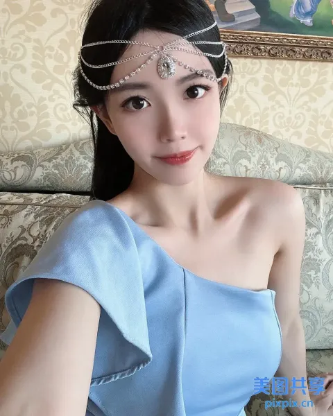 身穿蓝色连衣裙、戴着头饰的 araffe 女子坐在沙发上