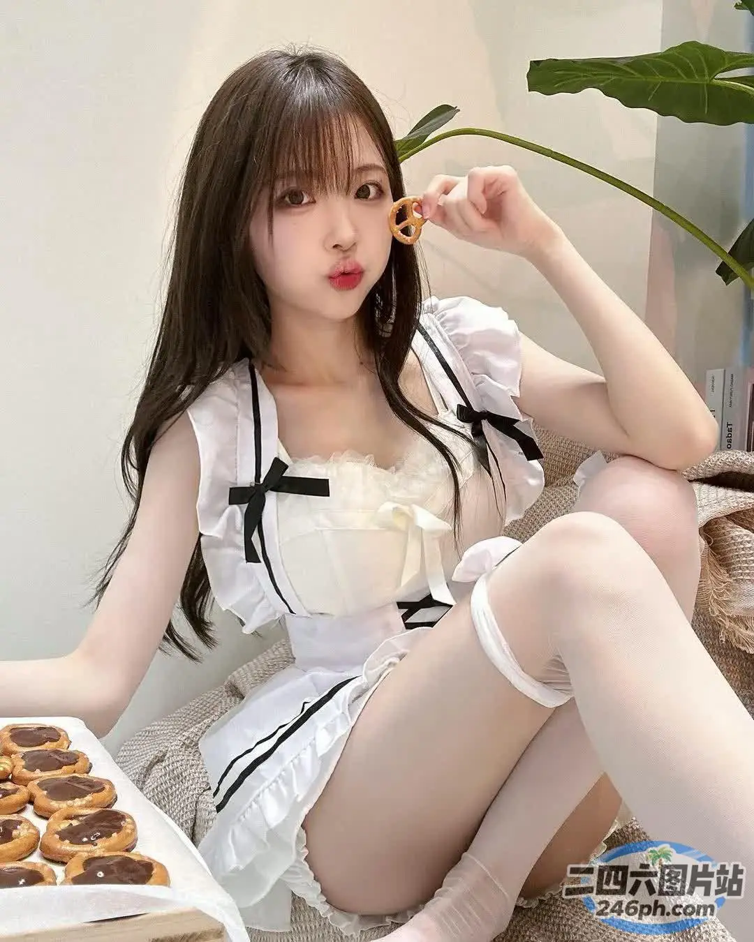 穿着白色连衣裙的 Araffe 女孩坐在床上，手里拿着一盒甜甜圈