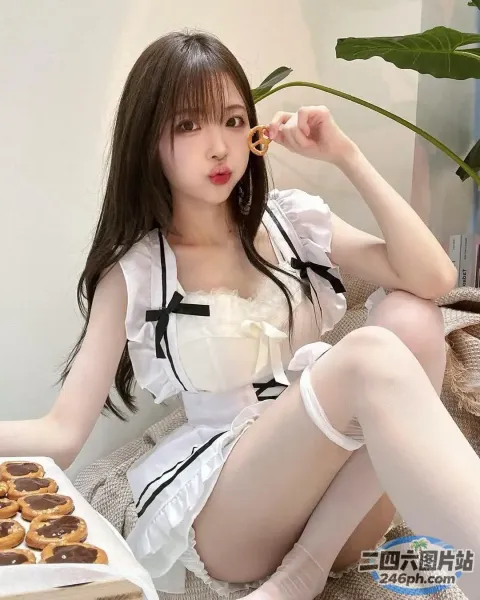 穿着白色连衣裙的 Araffe 女孩坐在床上，手里拿着一盒甜甜圈