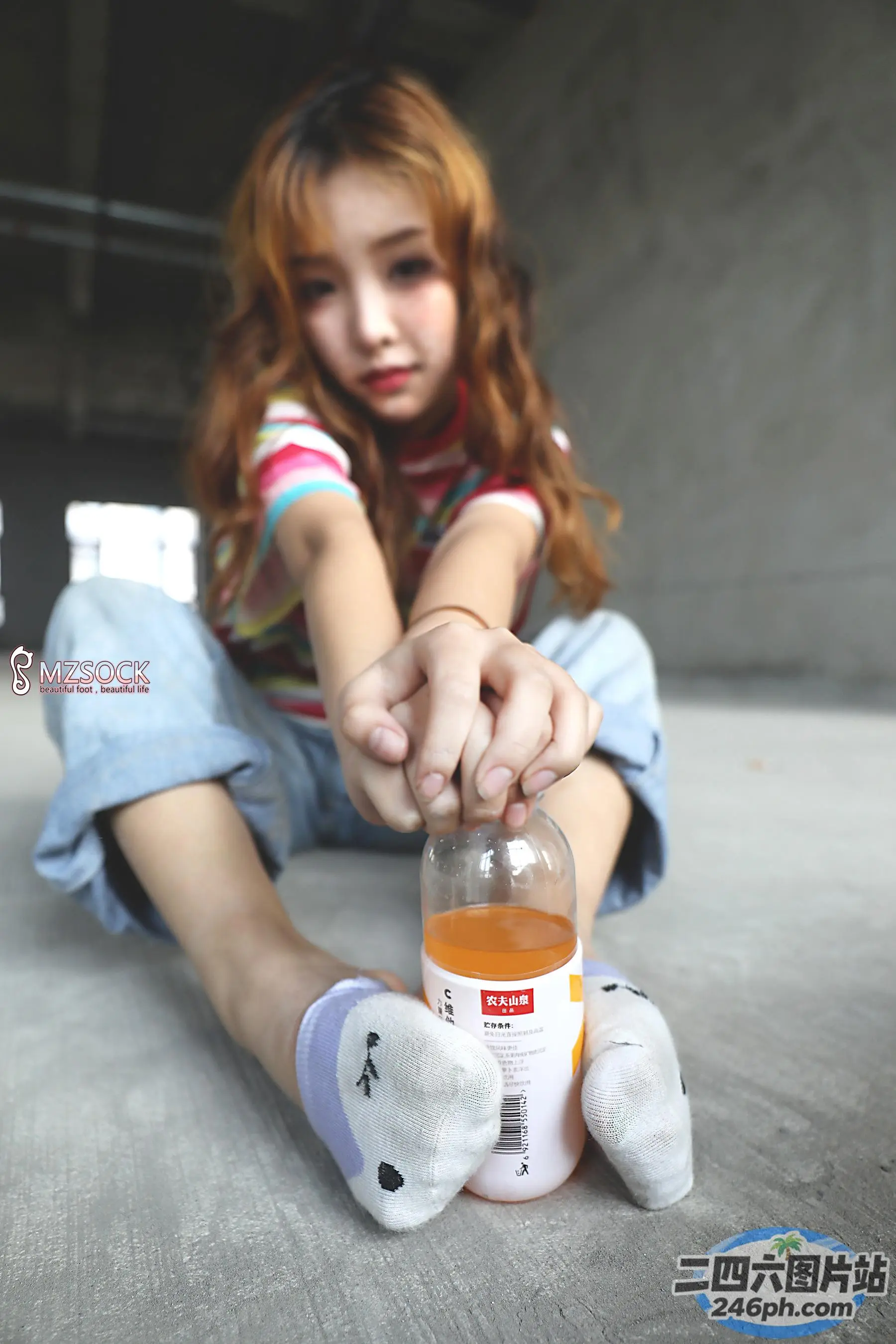 地板上坐着一个女孩，手里拿着一瓶液体