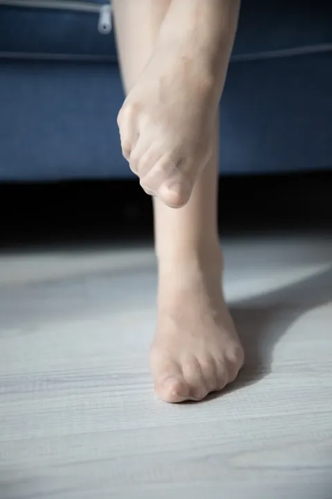 有一个人站在地板上，脚放在沙发上