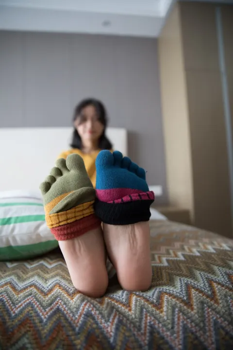 有一个女人坐在床上，双脚抬起
