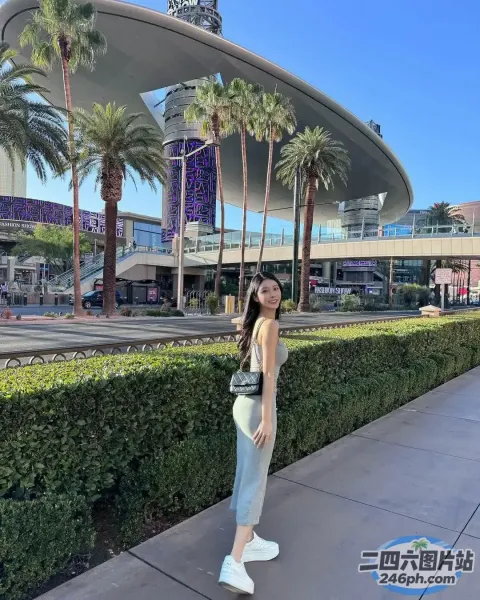 一名女子站在建筑物前的人行道上