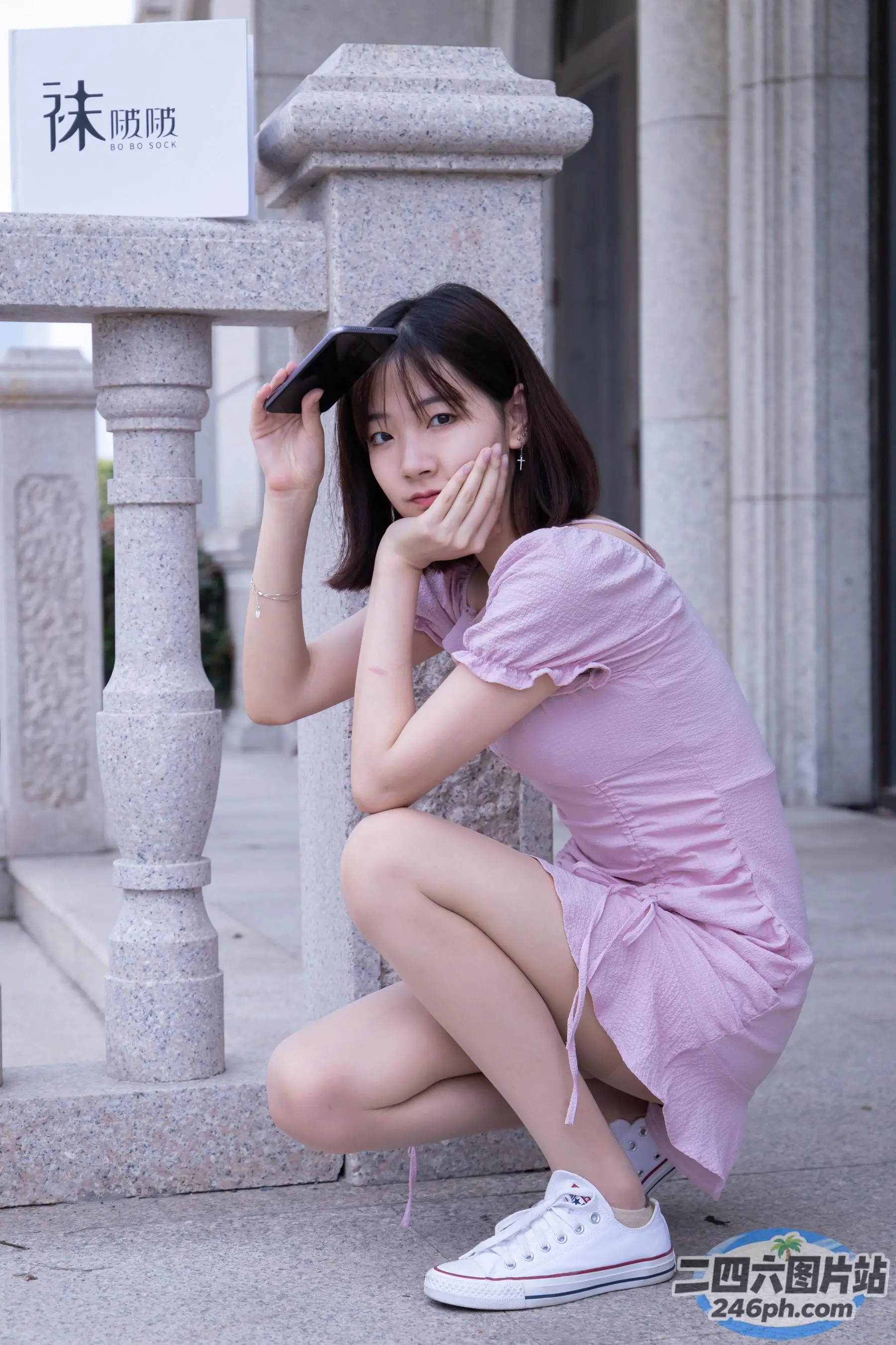 身穿粉红色连衣裙的 arafed 亚洲女子蹲在人行道上
