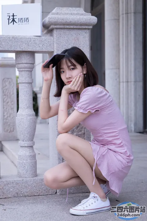身穿粉红色连衣裙的 arafed 亚洲女子蹲在人行道上