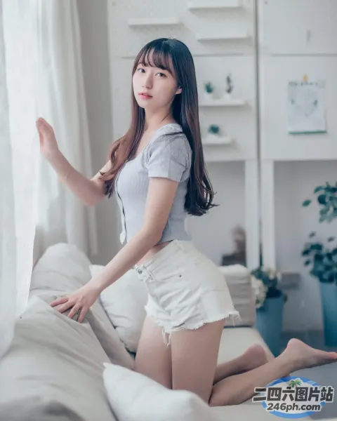 身穿白色短裤和灰色衬衫的 araffe 亚洲女性在沙发上摆姿势