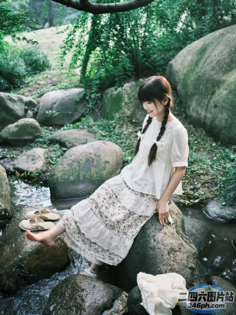 There is a woman on a rock in the water （有个女人坐在水中的一块岩石上）
