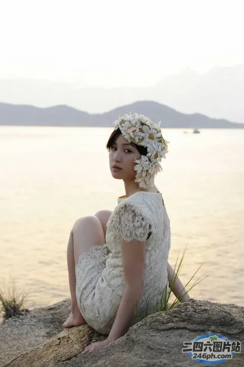一个女人坐在一块石头上，头发上插着一朵花