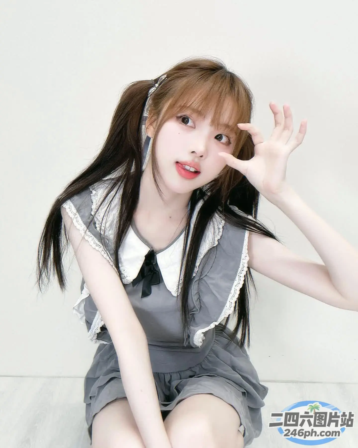 穿着灰色连衣裙的 arafed 亚洲女孩坐在白色地板上