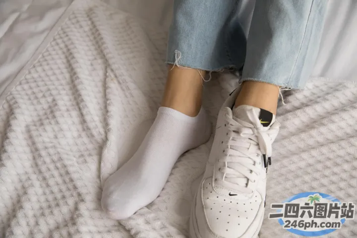 有人穿着白色运动鞋和牛仔裤躺在床上