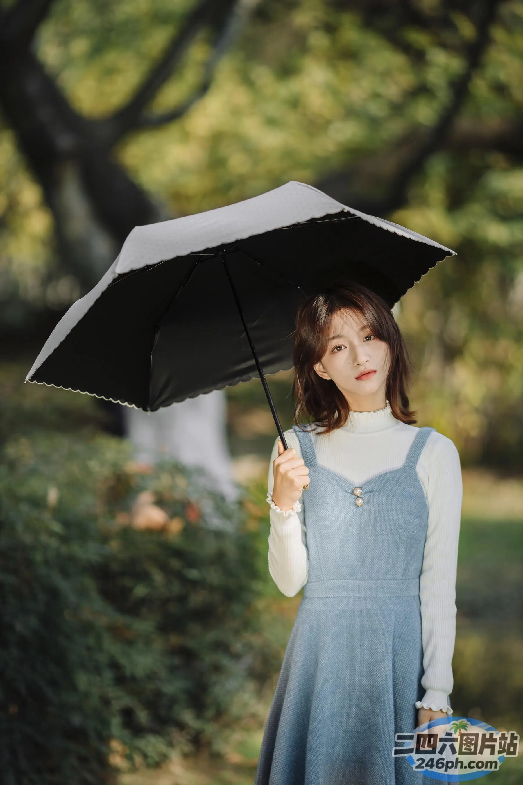 公园里穿着蓝色连衣裙的 Arafed 女子撑着伞