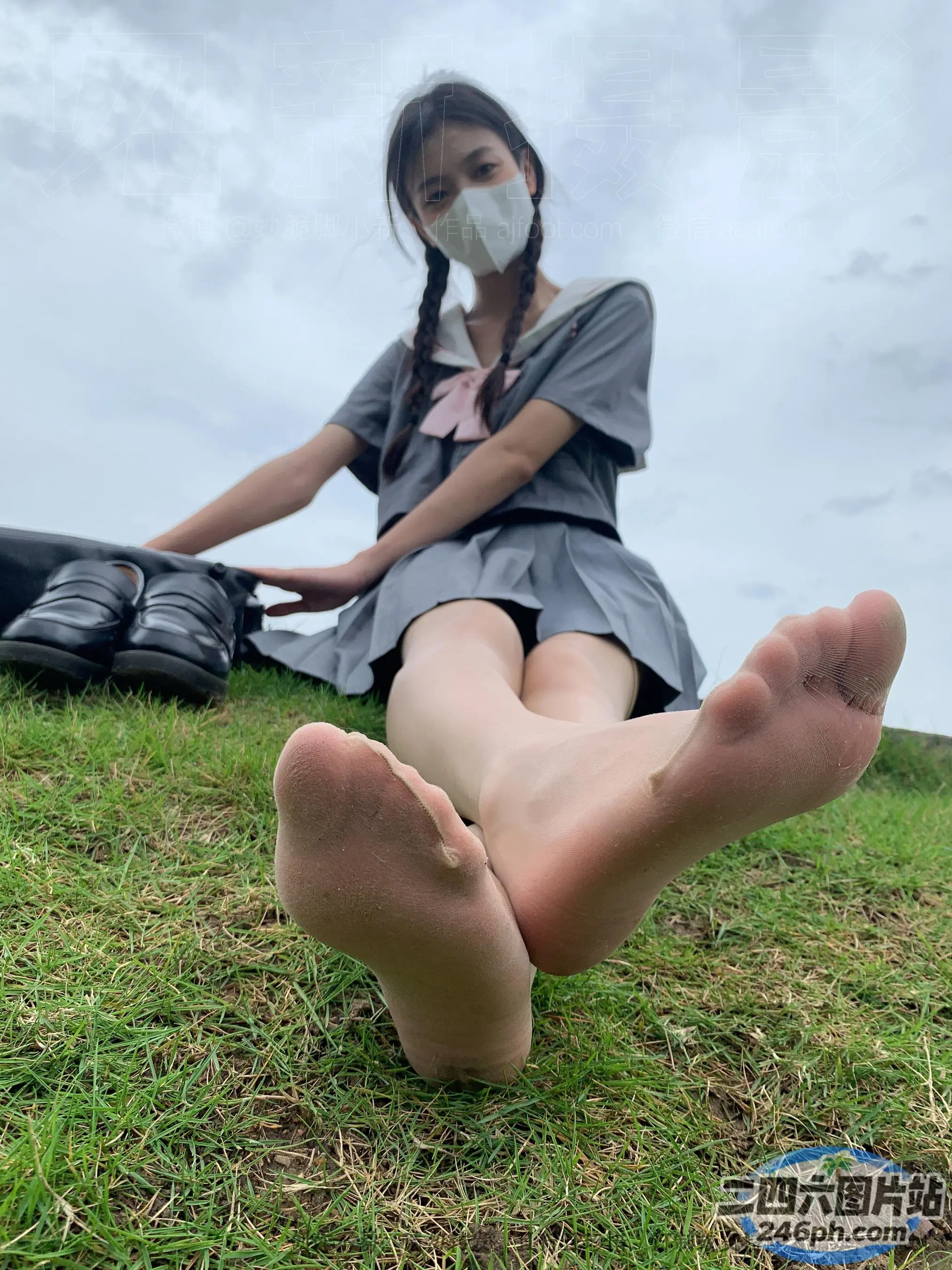 有一个女人坐在草地上，双脚抬起