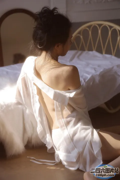 穿着白色长袍坐在地板上的 arafed 女人
