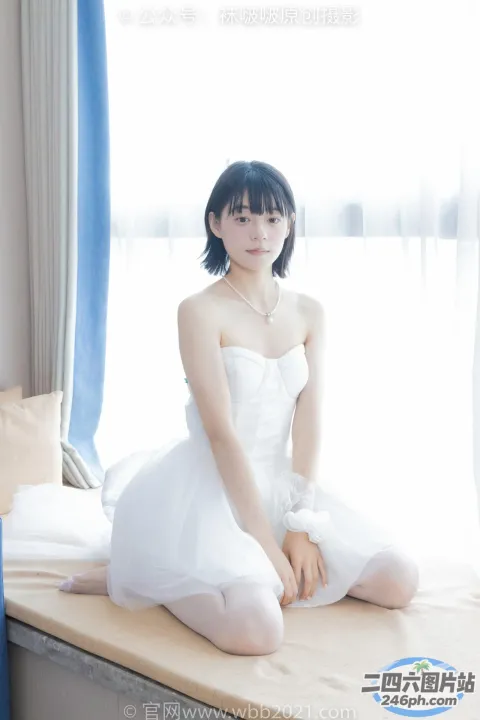 一个穿着白色连衣裙坐在床上的女人的特写