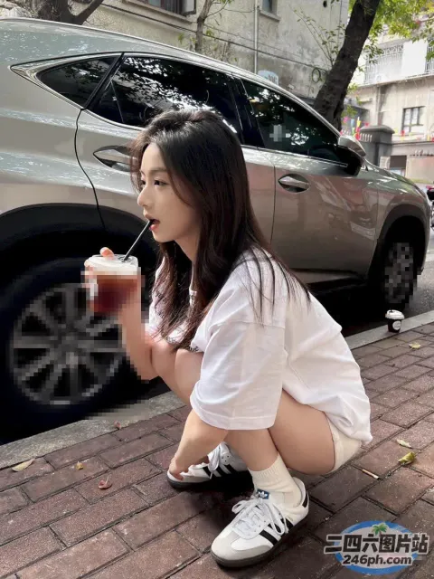 坐在人行道上喝酒的 Araffe 女孩
