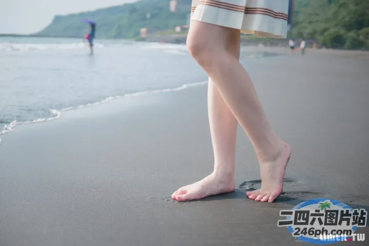 有一个女人站在沙滩上，双脚踩在沙子里