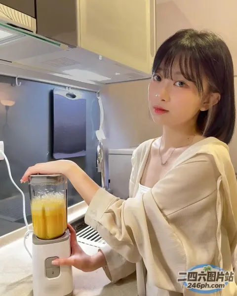 厨房里拿着装有橙汁的搅拌机的女人
