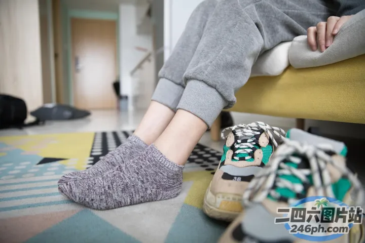 有人坐在沙发上，脚踩着一双鞋