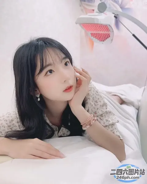 阿拉菲女人躺在一张床上，床上铺着白色的床单和一盏灯