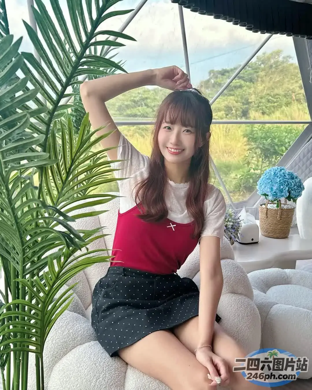 阿拉菲女孩坐在沙发上，手里拿着一本书和一棵植物