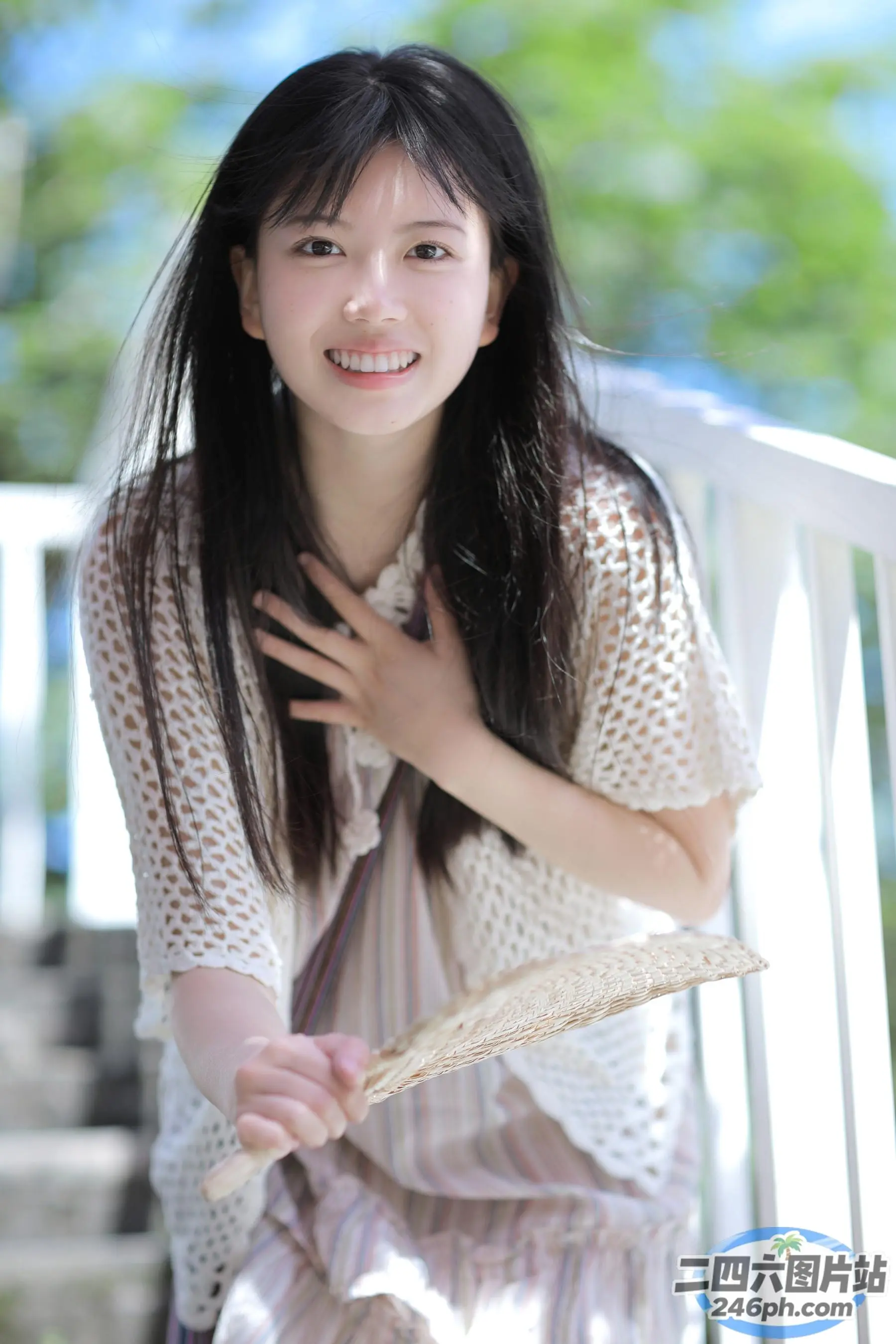阿拉菲女人坐在门廊上，拿着风扇，面带微笑
