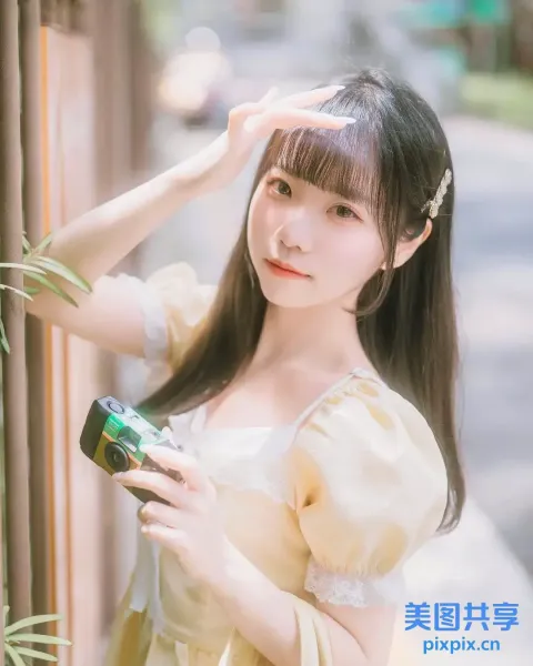 一个穿着黄色连衣裙的女人拿着相机的特写