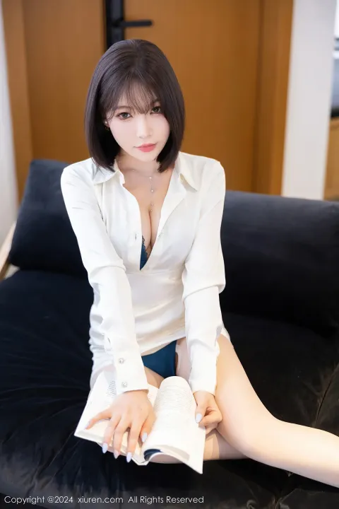一个女人坐在沙发上，手里拿着一本书