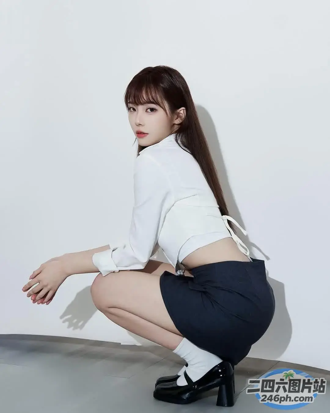 身穿白衬衫和黑色裙子的 araffe 女孩蹲下