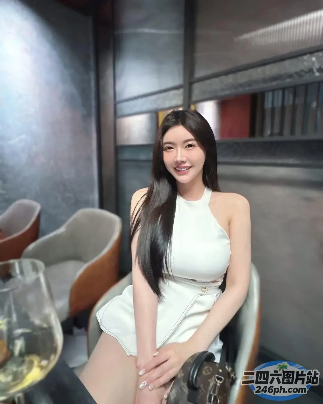 有个女人坐在椅子上，手里拿着一杯酒