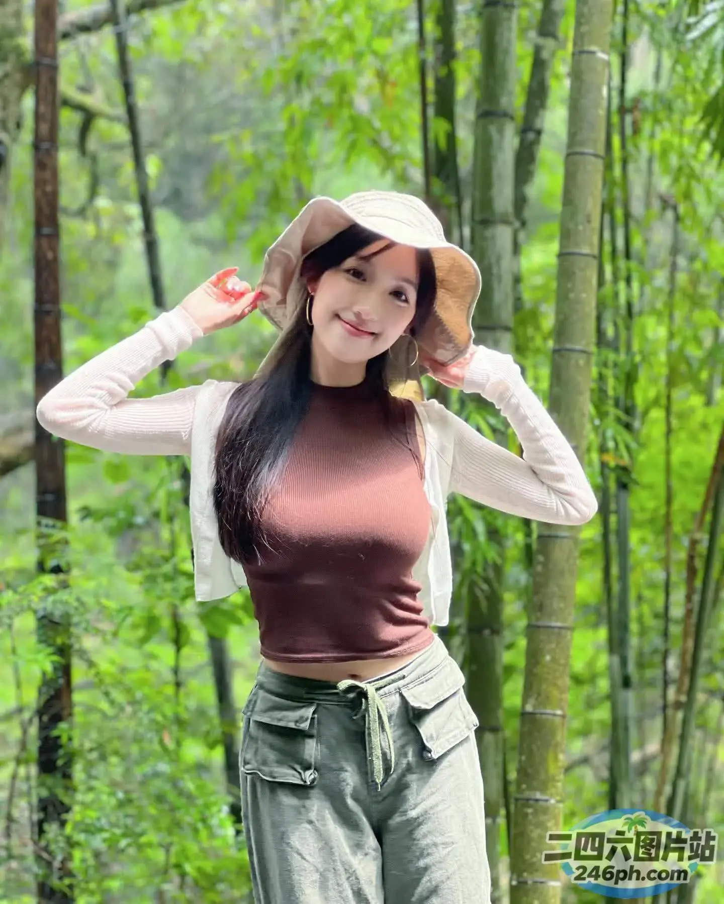 戴帽子和裤子的 Araffe 女人在竹林中摆姿势