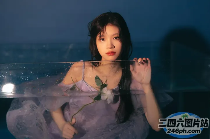 有一个穿着紫色连衣裙的女人，手里拿着一朵玻璃柜里的玫瑰