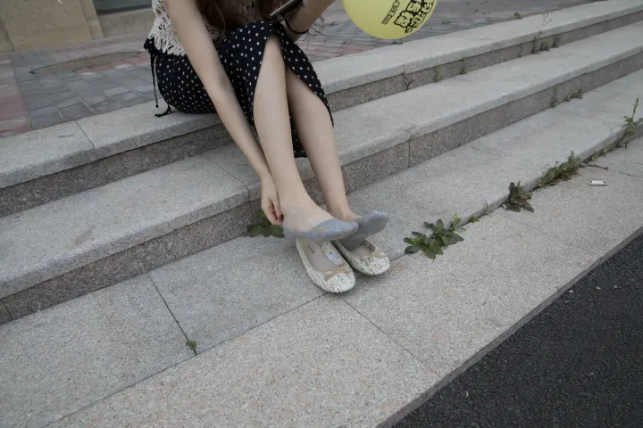 台阶上坐着一个女人，手里拿着一个黄色的气球