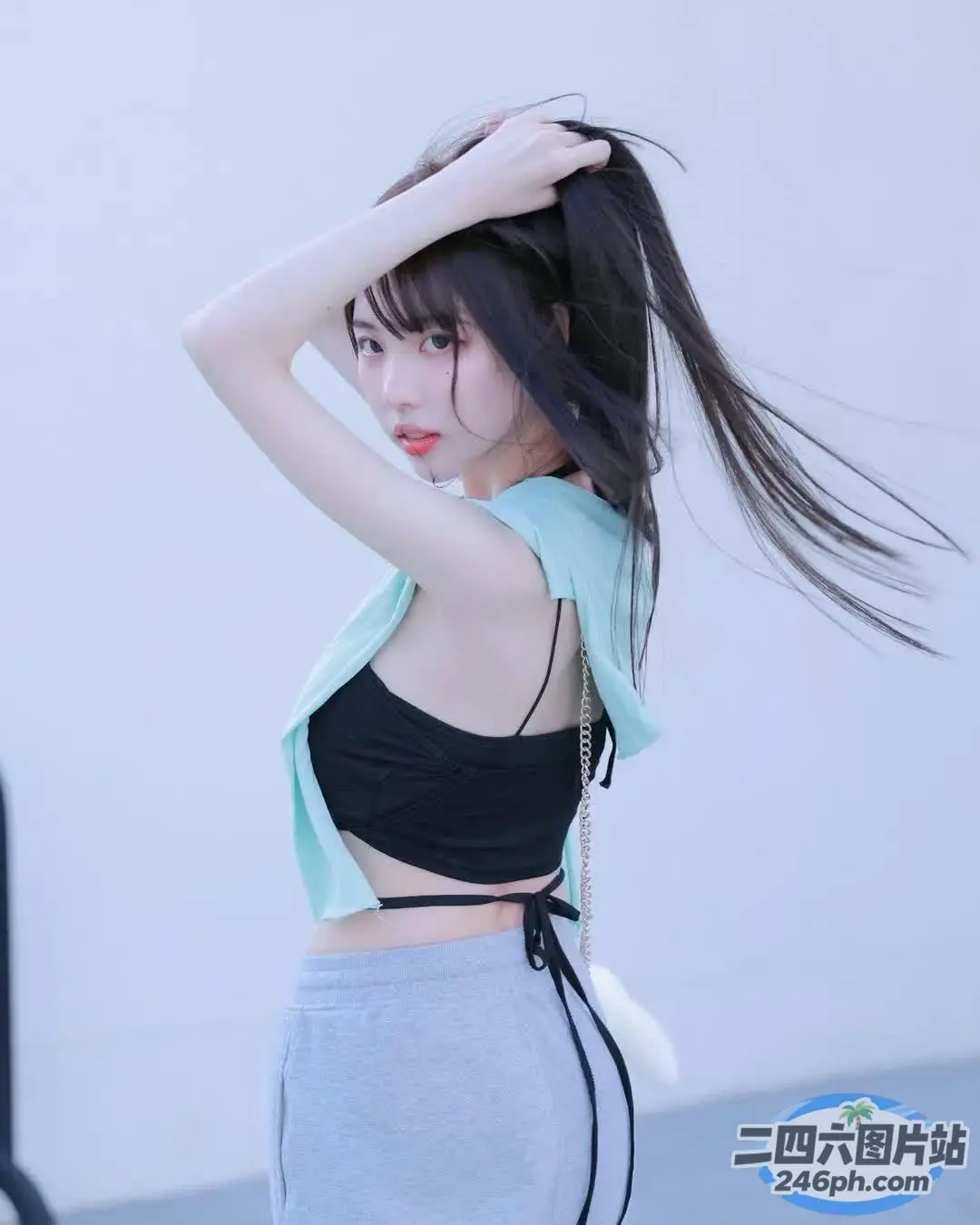 一名身穿黑色上衣和灰色裙子的女子摆姿势拍照