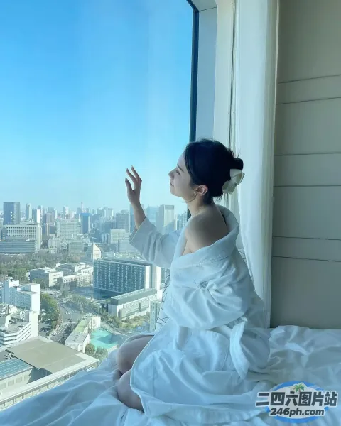 有一个女人坐在床上望向窗外