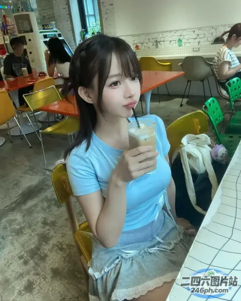 有个女人坐在桌子旁，手里拿着一杯饮料