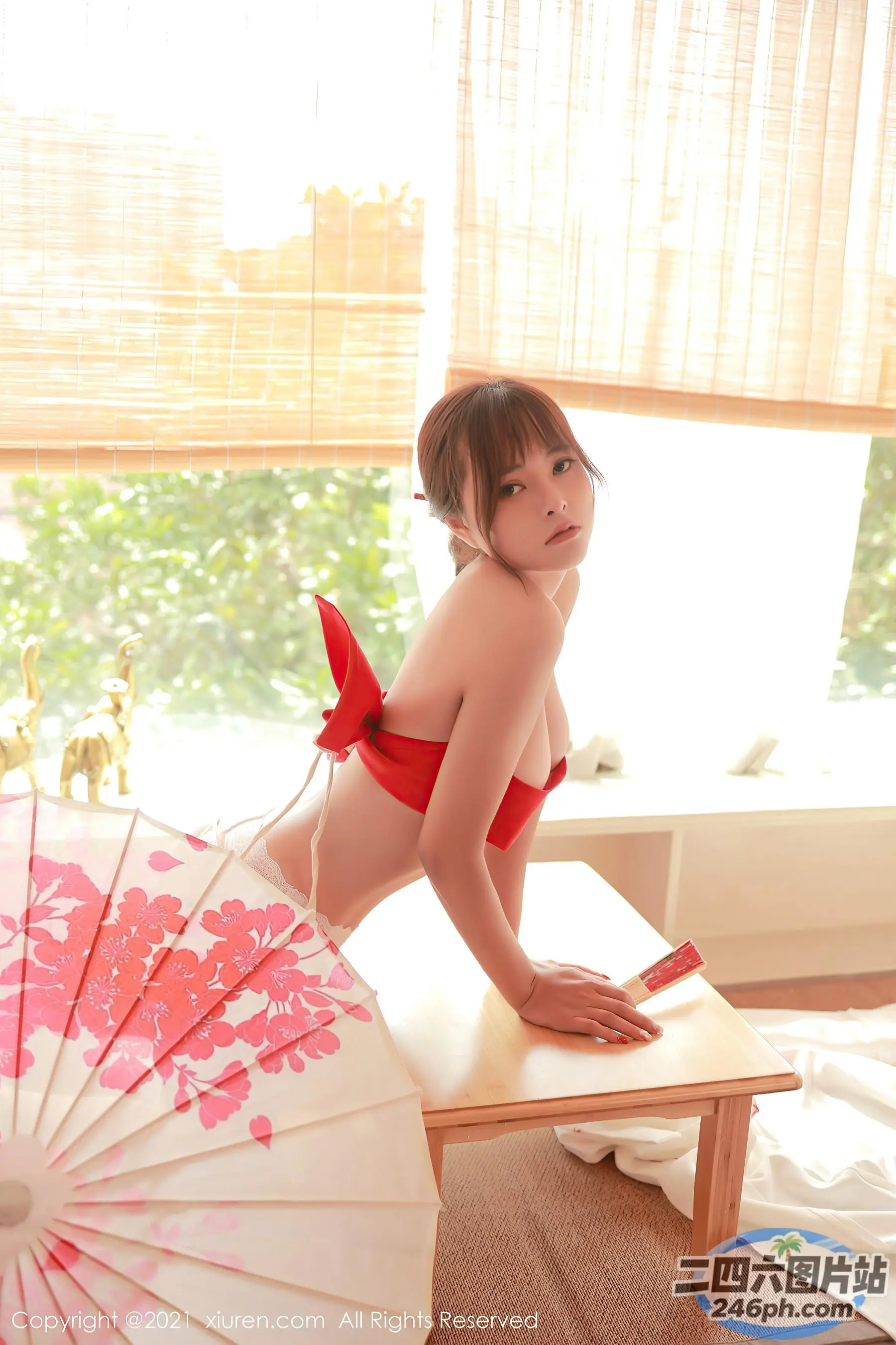 有一个穿着红色比基尼的女人坐在桌子上，手里撑着伞