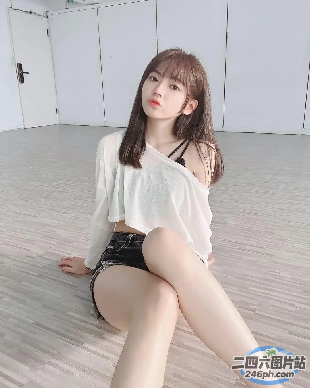 一名身穿白衬衫和黑色短裤的女子坐在地板上