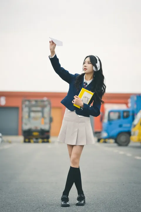 一个穿着校服的女人拿着一本书和一张纸