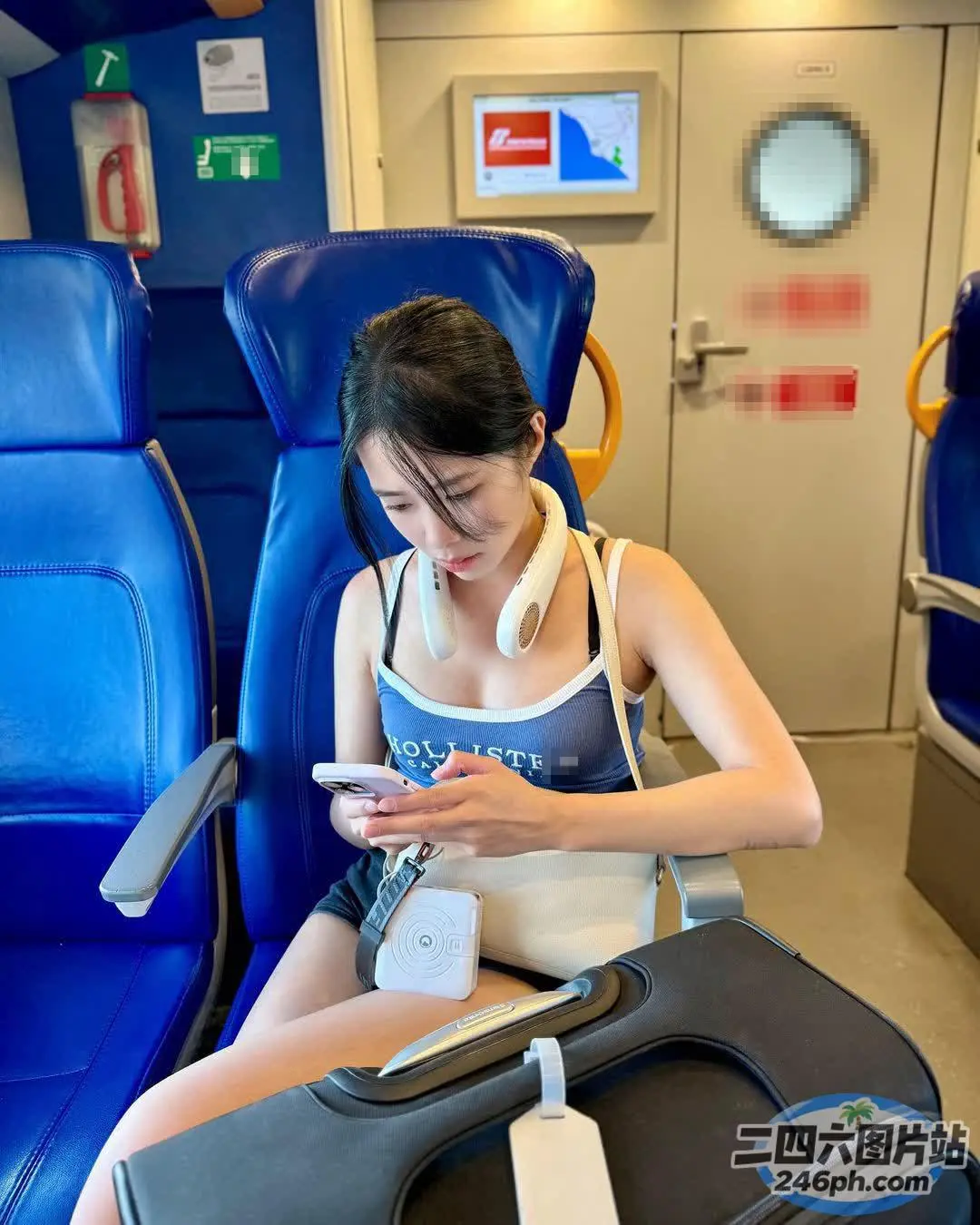 坐在火车上的阿拉菲德女人，戴着耳机，拿着手机
