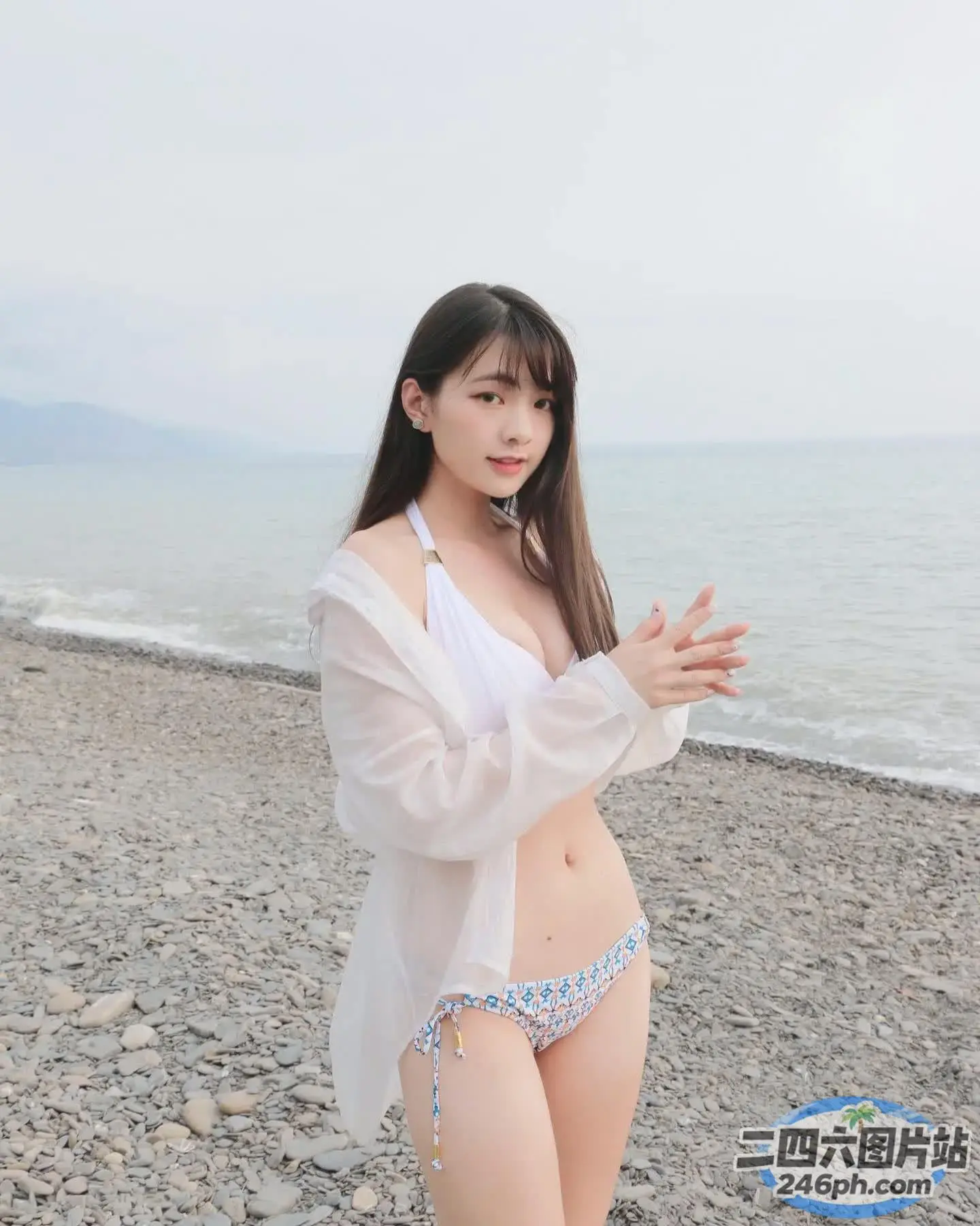 一名身穿白衬衫和蓝色比基尼的女子站在海滩上