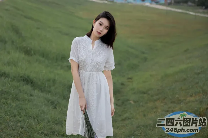 身穿白色连衣裙的阿拉伯女在田野里拿着一束花